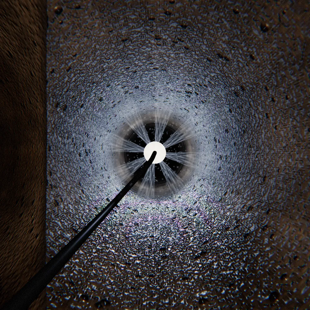 A jetting nozzle heading up a line, its rear jets spraying back along the pipe wall